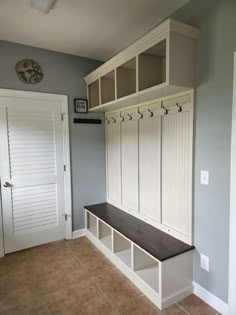 a room with a bench, coat rack and two doors on the wall next to it