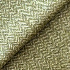 a close up view of a green and beige herringbone tweed fabric with an uneven pattern