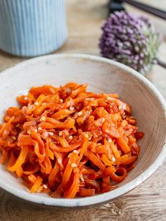 a white bowl filled with carrots on top of a wooden table