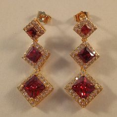 Beautiful Women's "Trilogy Luxury Design" Princess Cut Square Halo Garnet Ruby Red Zircon Drop Dangle Stud Earrings 18k Yellow Gold Filled + Tagged 925 Silver. Trilogy Three Sizes Ruby Red Square Shape Simulated Diamond Topaz Zircon Gemstones. Top Quality, High Polished Shine, Brand New, Never Been Worn. Lead, Nickel Free. These Gorgeous Earrings Sparkle. The "Trilogy" Design Represents Different Things To Different People - Past, Present, And Future, Relationships, Three Years Together, Three S Red Chandelier Earrings For Formal Events, Formal Red Chandelier Earrings, Red Chandelier Earrings As Gift, Red Crystal Earrings For Anniversary, Red Dangle Jewelry For Formal Occasions, Red Cubic Zirconia Earrings For Gift, Red Ruby Dangle Chandelier Earrings, Formal Red Cubic Zirconia Earrings, Red Ruby Dangle Earrings