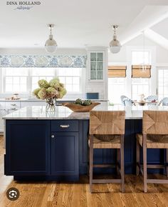 a large kitchen with blue cabinets and white counter tops, along with wooden flooring