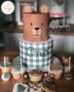 a bear themed birthday cake and cupcakes on a table