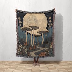 a woman is standing in front of a tapestry with mushrooms on it and the moon behind her