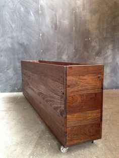 a large wooden box sitting on top of a cement floor next to a gray wall