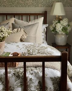 a bed with white flowers and pillows on top of it next to a night stand