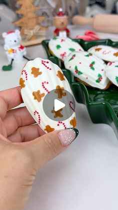 a person is holding a cookie in front of some other cookies on a table with christmas decorations