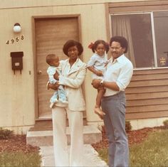 an old photo of a family standing in front of a house with the door open