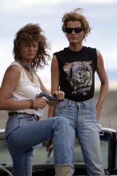 two women standing next to each other in front of a car