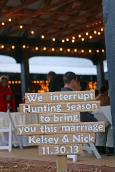 a wooden sign sitting on the side of a road next to a white table and chairs