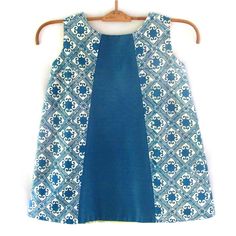 A classic little A-line dress-shape in a fresh mix of bright turquoise, hand-stamped Indonesian batik and two-tone cotton blend. Fully-lined with a back button enclosure. Size: 24-36 months 100% cotton Cold water wash; hang dry out of direct sunlight Blue A-line Dress With Patchwork, Blue Batik Print Sleeveless Dress, Blue Sleeveless Batik Print Dress, Blue Sleeveless Dress With Batik Print, Blue Batik Print Dress For Spring, Blue Cotton Patchwork Dress, Fitted Blue Block Print Dress, Fitted Blue Dress With Block Print, Blue Batik Print Cotton Dress