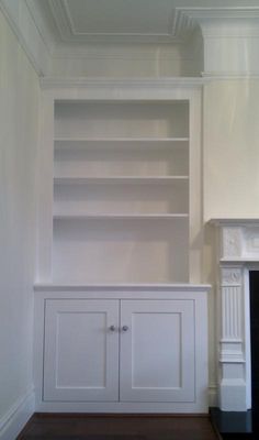 an empty room with white shelves and fireplace