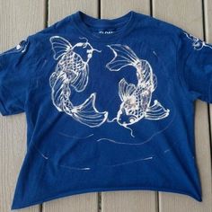 a blue t - shirt with two koi fish drawn on it's chest