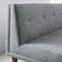 a gray couch sitting on top of a hard wood floor next to a white wall