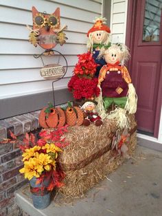 two scarecrows sitting on top of hay bales with pumpkins and flowers