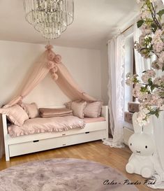 a white day bed with pink pillows and curtains on the top, next to a chandelier