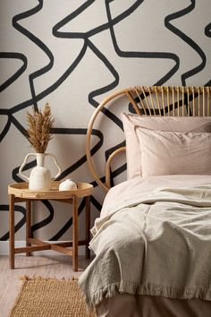 a bedroom with a bed, side table and wallpaper in black and white colors