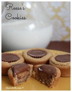 several cookies with chocolate frosting are on a yellow plate next to a white bowl