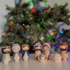 small wooden nativity figurines in front of a christmas tree