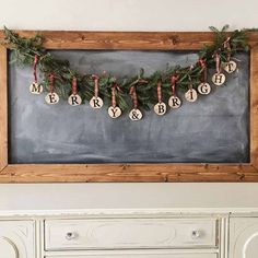 a chalkboard with christmas ornaments hanging from it's sides in front of a dresser