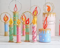 several colorful candles are lined up next to each other on a white surface with gold glitter around them