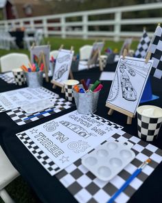 the table is set up with black and white checkered tables cloths, markers, cups, and pencils