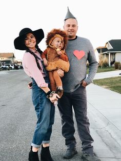 a man, woman and child are dressed up as lion and witch for halloween on the street