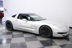 a white sports car sitting on top of a checkered floor