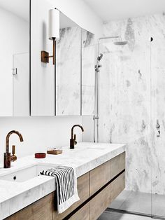 a bathroom with marble counter tops and two sinks in front of a walk - in shower