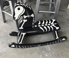 a rocking horse decorated with black and white skeleton paint is sitting on the floor in front of some bar stools