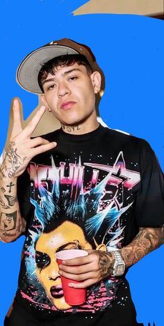 a man with tattoos and a hat holding a red cup in his right hand while making the peace sign