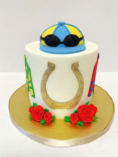 a cake decorated with a horseshoe, sunglasses and roses on a gold plated platter