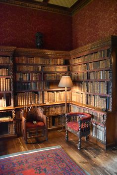 an old library with many books on the shelves and two chairs in front of it