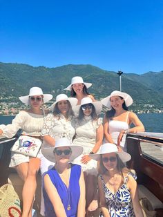 several women in white hats are sitting on the back of a boat and posing for a photo