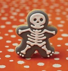 a cookie with a skeleton on it sitting on a polka dot tablecloth covered surface