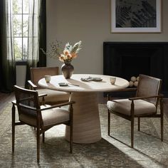 a dining room table with chairs and a vase on top of it in front of a fireplace