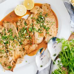 a white plate topped with meat covered in sauce and garnished with parsley