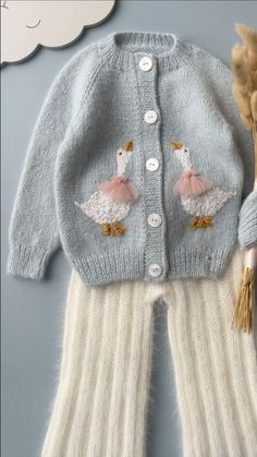 a knitted sweater and pants with two ducks on the front, along with a doll's head