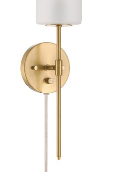 a gold wall light with a white shade on the side and a metal pole attached to it