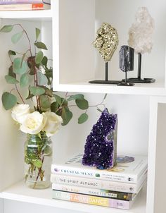 a vase filled with flowers sitting on top of a white book shelf next to books