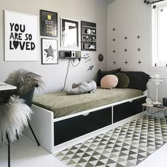 a bedroom with white walls, black and white decor and pictures on the wall above the bed