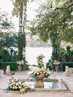 an outdoor fountain with flowers and greenery on it