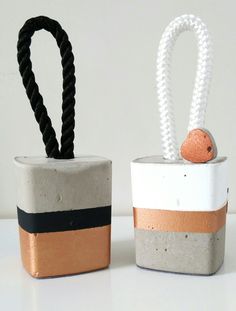 two small pots with handles made out of cement and rope, one has an odd shaped object in the middle