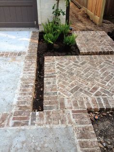 a brick walkway in front of a house with plants growing out of the cracks on it