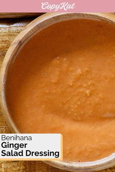 a wooden bowl filled with red sauce on top of a table next to a spoon