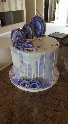 a white and blue cake sitting on top of a table next to a countertop