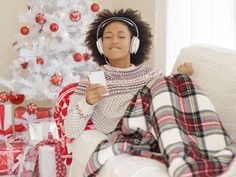 a woman listening to music while sitting in front of a christmas tree