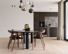 a dining room table with chairs and lights hanging from the ceiling