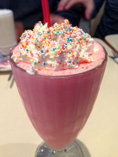 a pink drink with sprinkles on top and a straw in the cup