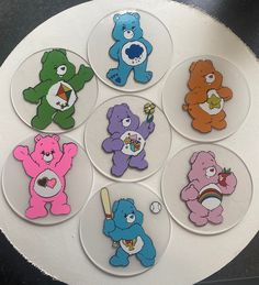 six different colored teddy bears sitting on top of a white plate with one holding a baseball bat