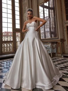 a woman in a white wedding dress standing on a checkered floor with her hands on her hips